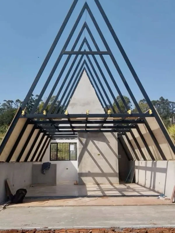 Estrutura metálica A-frame em fase de construção com paredes brancas